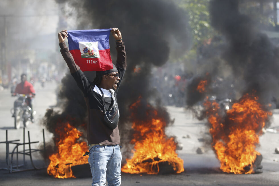 En demonstrant holder opp et haitisk flagg under protester som krever statsminister Ariel Henrys avgang i Port-au-Prince, Haiti, fredag 1. mars 2024.
 Foto: AP Photo/Odelyn Joseph/NTB.