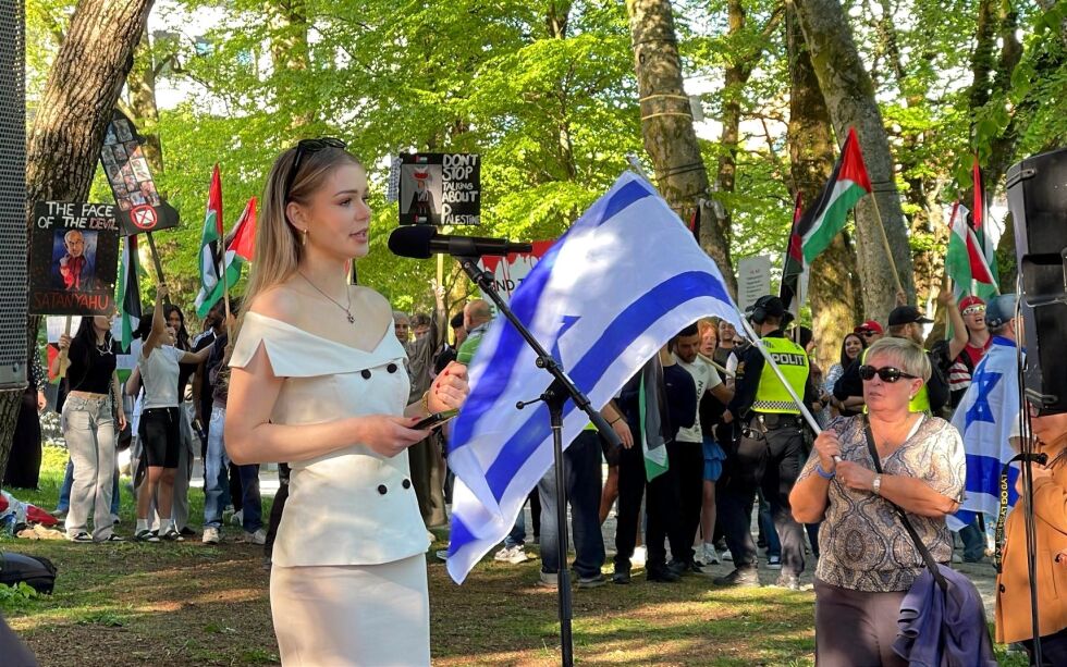 TALTE PÅ ISRAELS NASJONALDAG: Kristin Lode har markert seg som israelvenn. I bakgrunnen anti-Netanyahu-plakat.
 Foto: Privat