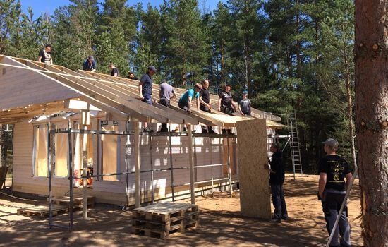 GÅR UNNA: 19 elever og seks ledere fra Bygland kristne videregående skole i full sving med å reise den fjortende hytta på leirstedet Latgales Dzintars i det østlige Latvia.
 Foto: John Solsvik