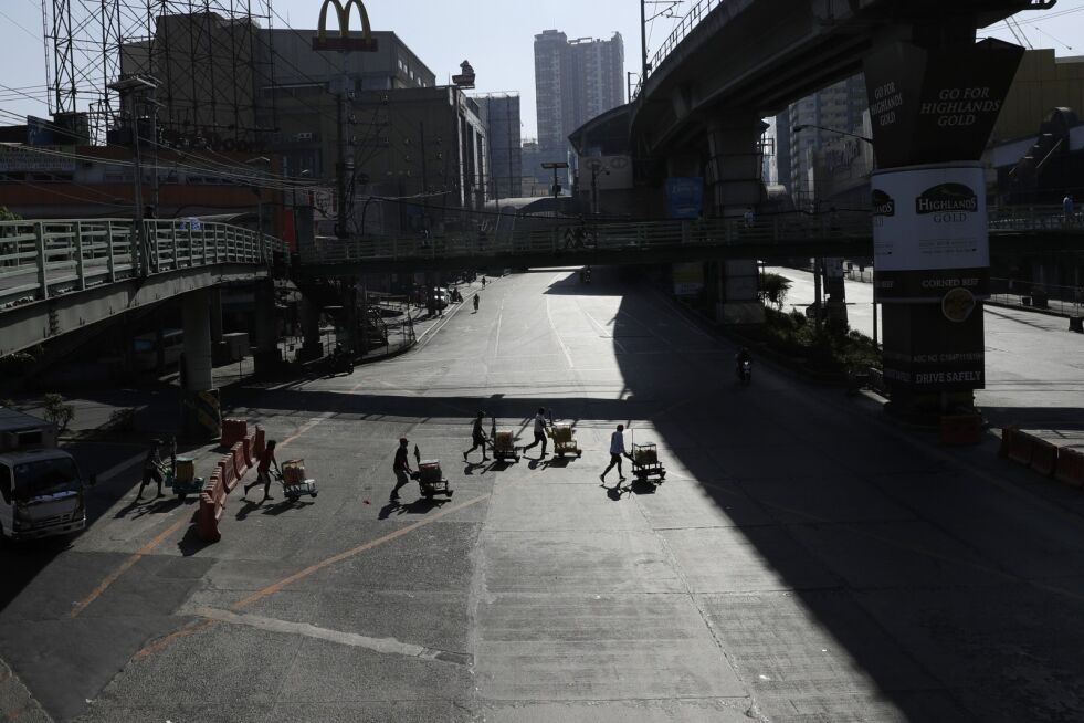 Personer med handlevogner på en nesten tom motorvei i Manila på Filippinene. Foto: Aaron Favila / AP / NTB scanpix