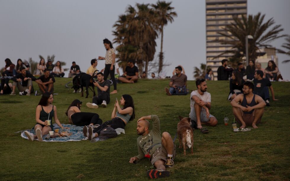 Mennesker uten ansiktsmasker nyter solnedgangen i Tel Aviv, søndag 18. april 2021.
 Foto: Oded Balilty / NTB