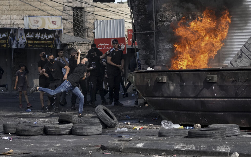 Palestinere i kamp med israelske sikkerhetsstyrker etter at hæren inntok Shuafat flyktningeleir mandag 10 oktober 2022. Det foregår en jakt på gjerningsmannen som åpnet ild mot et kontrollpunkt i Øst-Jerusalem og drepte en 18 år gammel soldat og såret tre andre.
Foto: NTB/AP Photo/Mahmoud Illean