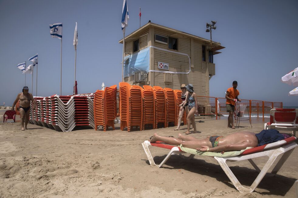 TEL AVIV: Et stort munnbind er hengt opp på veggen på livvakt-tårnet på stranda, for å minne folk om smitteverntiltakene under korona-epidemien. Nå skal strendene stenges i helgene, som et av flere nye tiltak.
 Foto: AP / NTB Scanpix