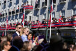 Mennesker vinker fra Grand Hotel idet barnetoget går opp Karl Johans gate under 17. maifeiringen i Oslo. Foto: Javad Parsa / NTB
