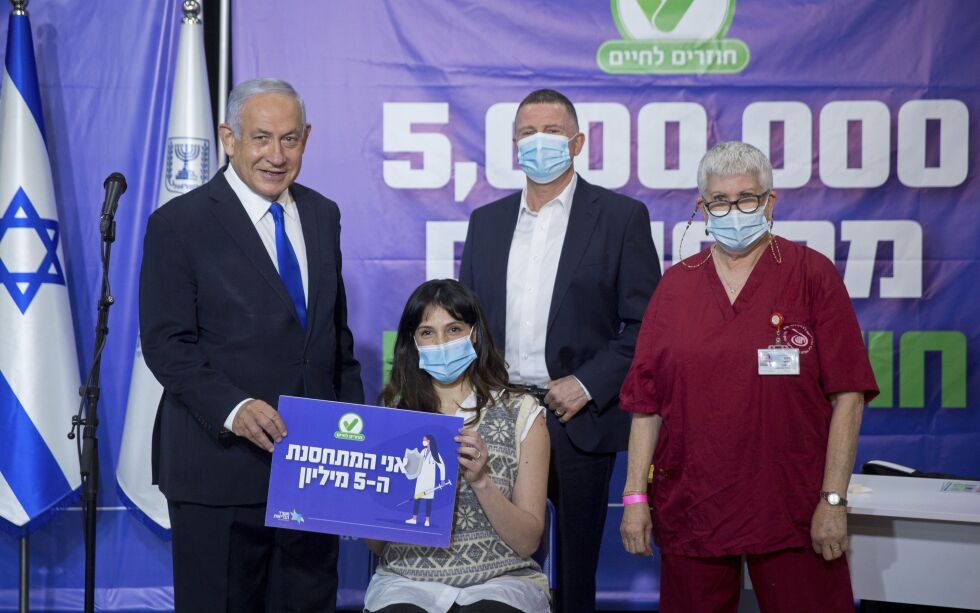 Israels statsminister Benjamin Netanyahu (t.v.) og helseminister Yuli Edelstein (bak i midten) står sammen med personen som markerte at 5 millioner mennesker var blitt vaksinert mot covid-19. Det vellykkede vaksineprosjektet i Israel kan komme til å sikre Netanyahus gjenvalg 23. mars.
 Foto: Miriam Alster / NTB