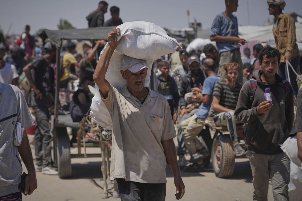 Palestinere bærer mat- og humanitære hjelpepakker levert av Gaza Humanitarian Foundation, en USA-støttet organisasjon, i Rafah, sørlige Gazastripen, torsdag 26. juni 2025.
 Foto: AP Photo/Abdel Kareem Hana/NTB