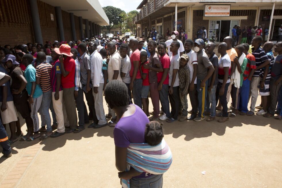 Zimbabwes innbyggere har valget mellom sult eller koronasmitte. Disse står i kø utenfor et supermarked i Harare, i håp om å få kjøpe maismel, som det er mangel på i landet.
 Foto: NTB scanpix