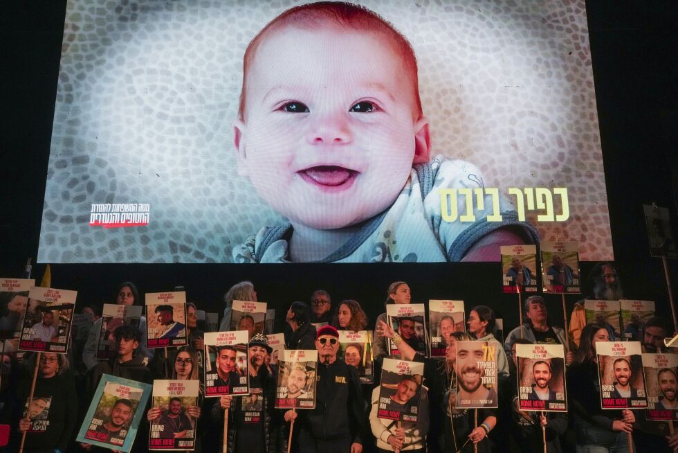 Aktivister i Tel Aviv med plakater av gisler som ble tatt til fange av Hamas 7. oktober 2023. På det store bildet i bakgrunnen er Kfir Bibas, som sammen med sin familie har vært over 15 måneder i fangenskap i Gaza. – Gisseltaking er en krigsforbrytelse etter Genèvekonvensjonen, skriver Ragnar Hatlem.
 Foto: NTB / AP / Ohad Zwigenberg