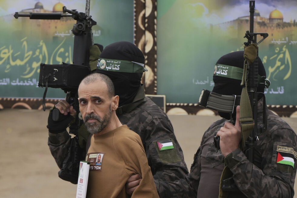 Den israelske fangen Eli Sharabi, som har blitt holdt som gissel av Hamas i Gaza siden 7. oktober 2023, blir her eskortert av Hamas-krigere før han blir overlevert til Røde Kors lørdag.
 Foto: NTB/AP