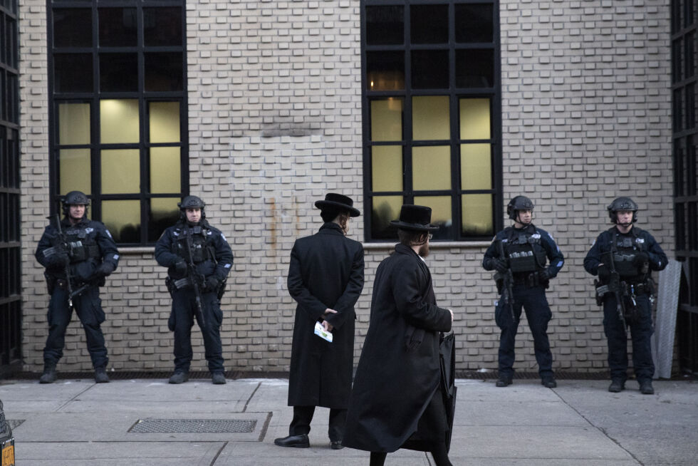 NEW YORK: Ortodokse jødiske menn passerer politistyrker som vokter en synagoge i Brooklyn.
 Foto: NTB/AP