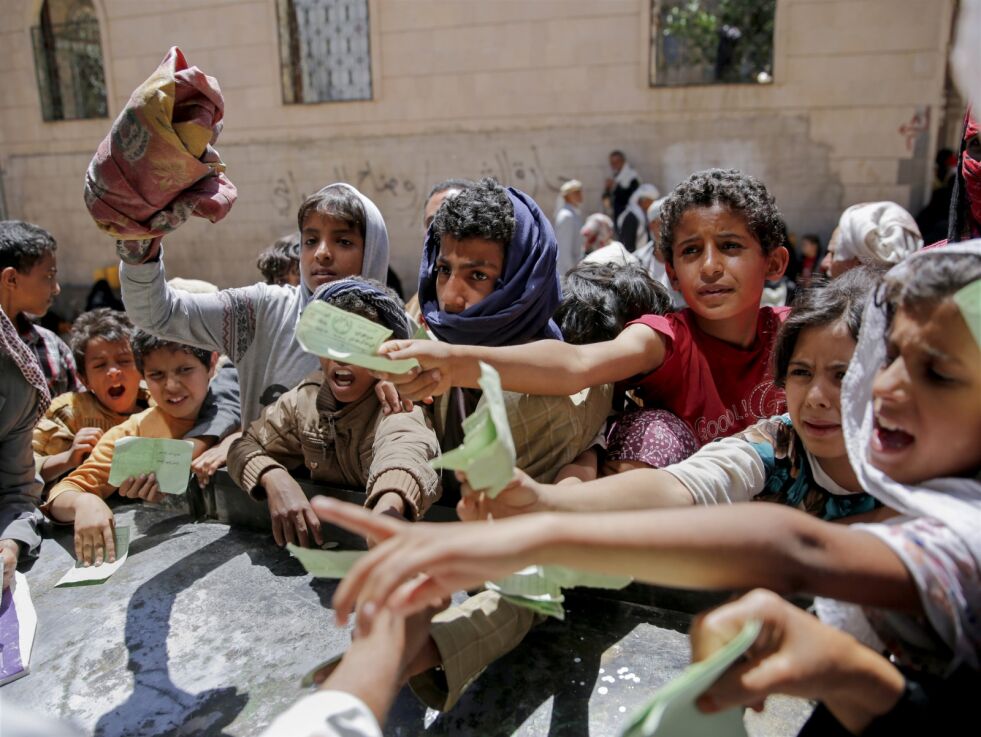 Innbyggere i Jemens hovedstad Sanaa rekker frem ID-papirer for å motta matkuponger fra en hjelpeorganisasjon.
 Foto: AP / NTB Scanpix