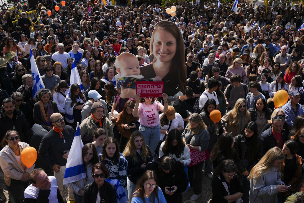 Folk ser en direktesending fra begravelsen til de drepte gislene Shiri Bibas og hennes to barn, Ariel og Kfir, på et torg kjent som Gisselplassen i Tel Aviv, Israel, onsdag 26. februar 2025.
 Foto: AP Photo/Ariel Schalit/NTB