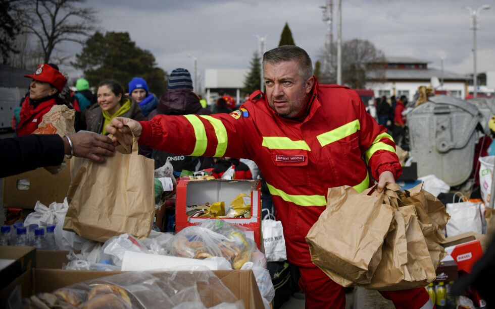 FLYKTNINGER: En hjelpearbeider deler ut mat til ukrainske flyktninger på grensen til Romania.
 Foto: Andreea Alexandru / AP / NTB