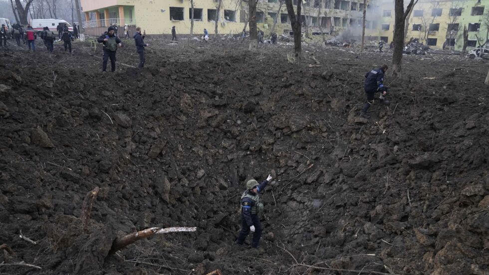 Ukrainske soldater og hjelpearbeidere står i ødeleggelsene utenfor et fødehjem som ble hardt skadd etter et angrep i Mariupol i mars. Bildet er tatt 9. mars. Foto Jevgenij Maloletka / AP / NTB