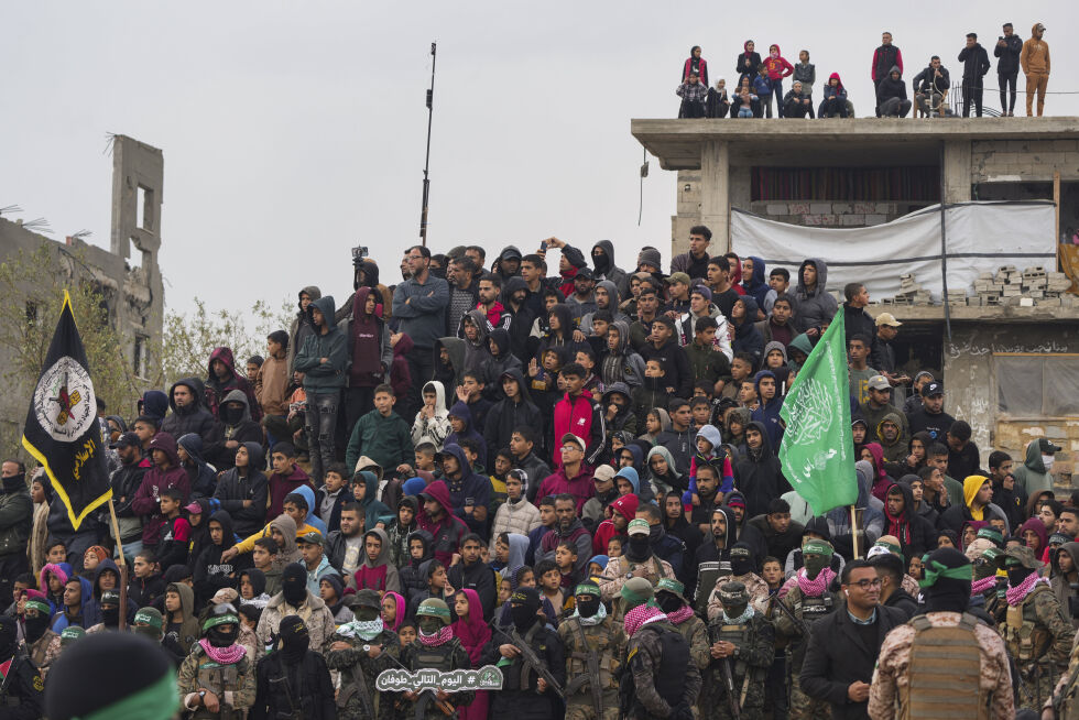 Palestinere samles mens Hamas-krigere stiller seg opp i forkant av overleveringen av fire lik til Røde Kors i Khan Younis, sør på Gazastripen, torsdag 20. februar 2025. Israel har identifisert tre av likene som gisler og sa at den siste var av en ukjent person.
 Foto: AP Photo/Abdel Kareem Hana/NTB
