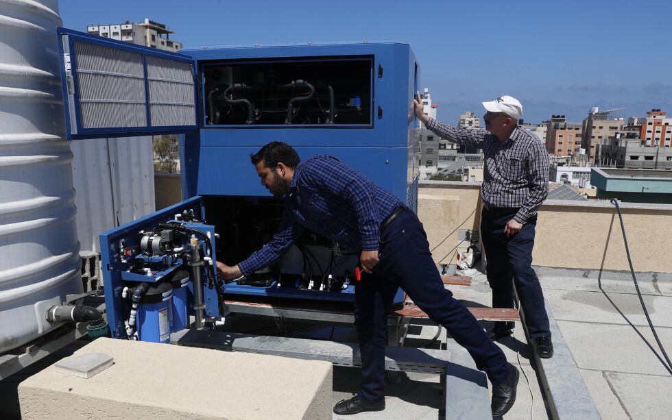 Den palestinske ingeniøren Raed Nakhal fra Palestine Children Relief Fund, til høyre, og ingeniør Abdullah Dewik sjekker GEN-M-maskinen som genererer trygt drikkevann fra luften på taket til al-Rantisi sykehus i Gaza. Den israelske milliardæren Michael Mirilashvil tror han har funnet en løsning på Gazastripens kroniske vannkrise. Selskapet hans, Watergen, ønsker å levere hundrevis av generatorer som produserer drikkevann ut av løse luften. De har allerede levert to av maskinene til Gaza til tross for at det er terrororganisasjonen Hamas som har kontrollen over enklaven. Illustrasjonsbilde.
 Foto: Adel Hana/AP/NTB