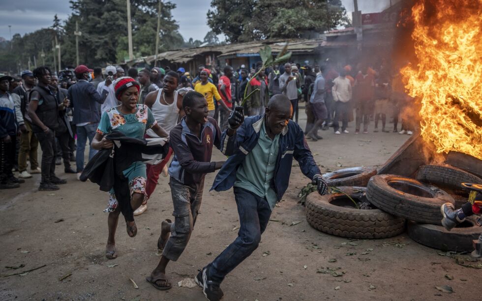 Tilhengere av presidentkandidat Raila Odinga løper forbi brennende bildekk i Kibera-slummen i Nairobi. Det brøt ut protester flere steder i Kenya etter at William Ruto ble utropt til vinner av presidentvalget.
 Foto: Ben Curtis/Ap/NTB