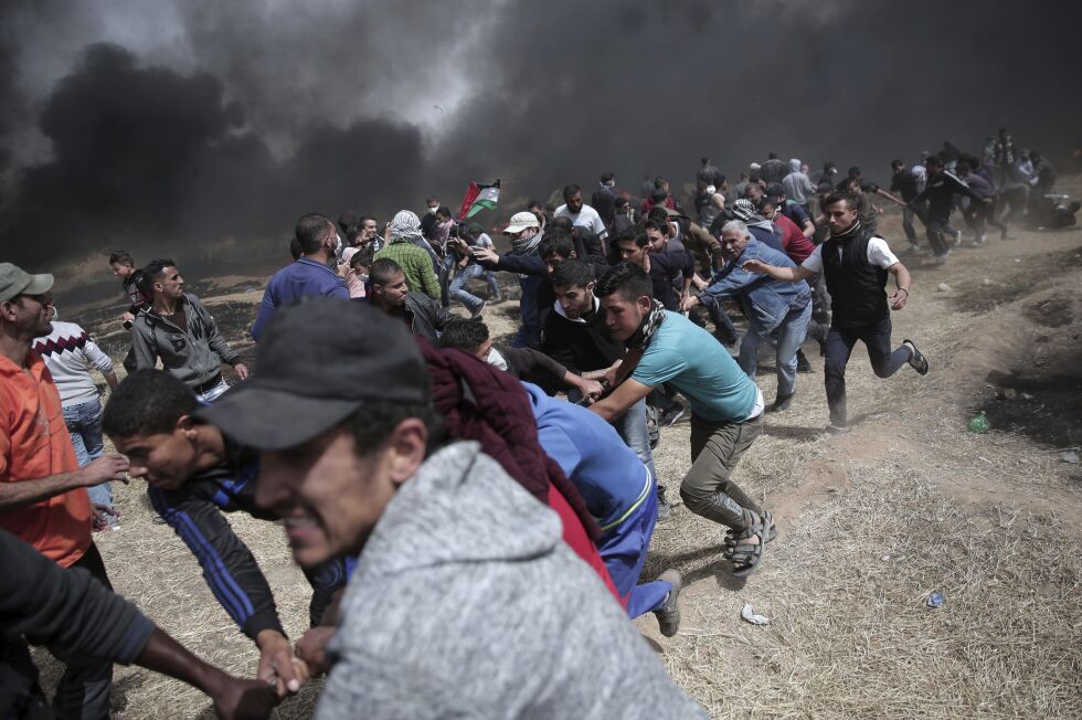 OPPTØYER: Her forsøker en gruppe palestinske demonstranter å rive ned grensegjerdet mellom Israel og Gaza. Foto: AP / NTB Scanpix