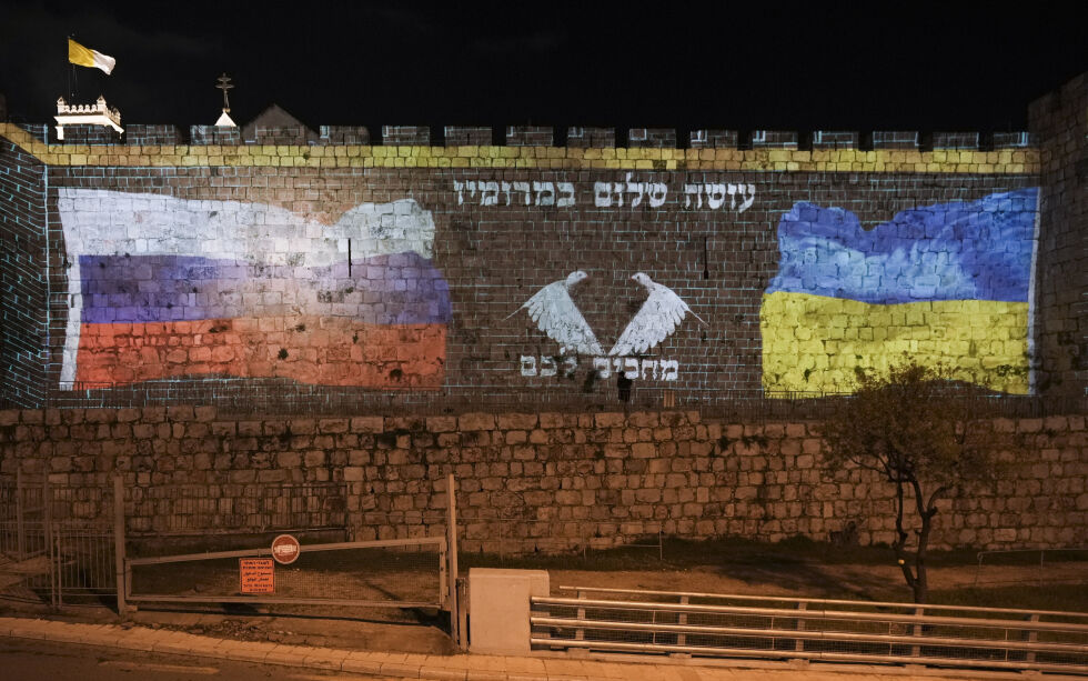 En prosjektor viste flaggene til Russland og Ukraina på muren i Gamlebyen i Jerusalem 13. mars 2022. På hebraisk står det «Ber for fred, venter på deg.»
 Foto: NTB/AP Photo/Mahmoud Illean