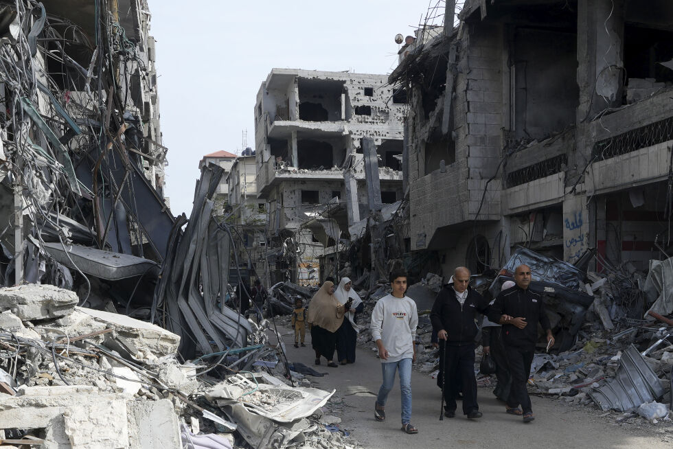 Palestinere går forbi ødelagte bygninger i Nusseirat-leiren sentralt på Gazastripen.
 Foto: Adel Hana / AP / NTB