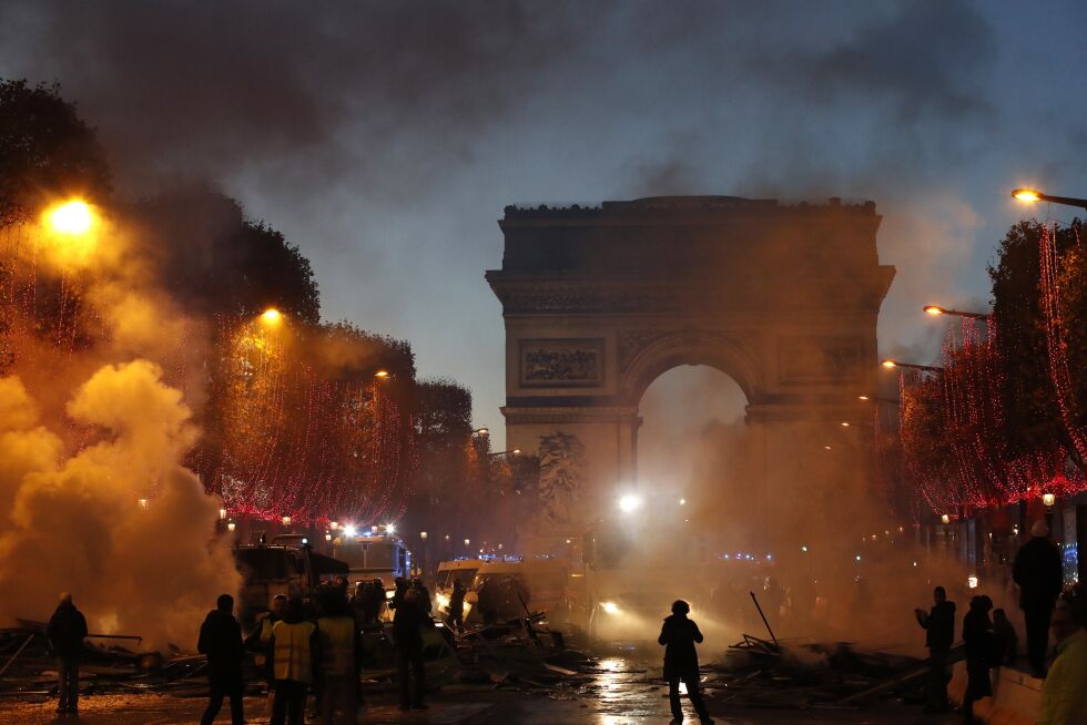 bølger av røyk: Røyk nær Triumfbuen på Champs-Elysees. Demonstrasjonen lørdag 24. nov i Paris samlet tusener mot økning i bensinavgiftene. Politiet skjøt med tåregass for å spre voldelige demonstranter.
 Foto: AP/Christophe Ena