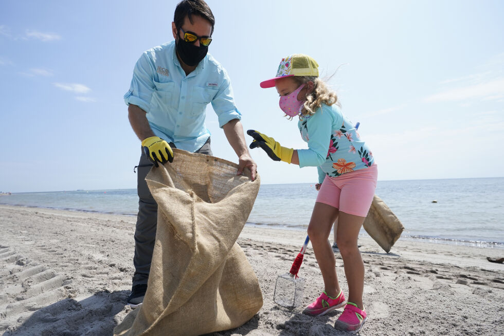 Ed Prichard og Charlotte Gonzalez plukker søppel og mikroplast mens de deltar i en Earth Day-strandopprydding i Florida.
 Foto: NTB/AP/Wilfredo Lee