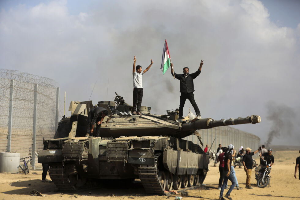 FORHANDLINGER AVBRUTT: – Et trist bevis på skaden forårsaket av FNs sikkerhetsråds resolusjon, sier Netanyahus kontor om bruddet i forhandlingene. På bildet vifter palestina-arabere med flagget og feirer med en ødelagt israelsk stridsvogn ved gjerdet sør på Gazastripen øst for Khan Younis 7. oktober.
 Foto: NTB/AP Photo/Yousef Masoud
