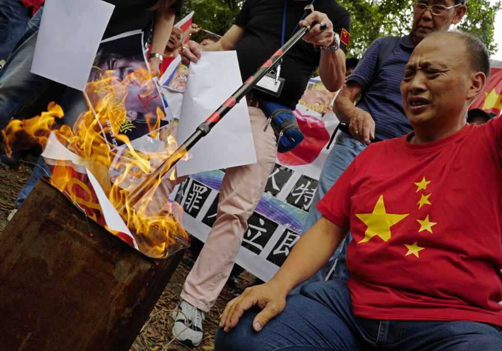 Forbud mot bøker: Det er en moderne form for bokbål man nå er vitne til i Kina. Mandag sist uke kom nyheten om at kommunistpartiet krevde en oppsporing (og ødeleggelse) av alle religiøse bøker. Det er farlig og trist, men også flaut å oppleve det i 2021. Bilde av pro-kinesiske demonstranter som brenner vestlige plakater i Hong Kong (okt. 2018).
 Foto: NTB